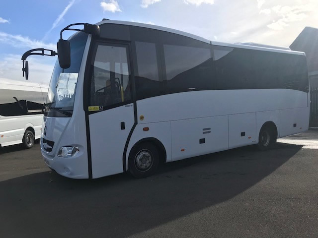 Pre-owned white and grey midi coach in the yard, ready for sale