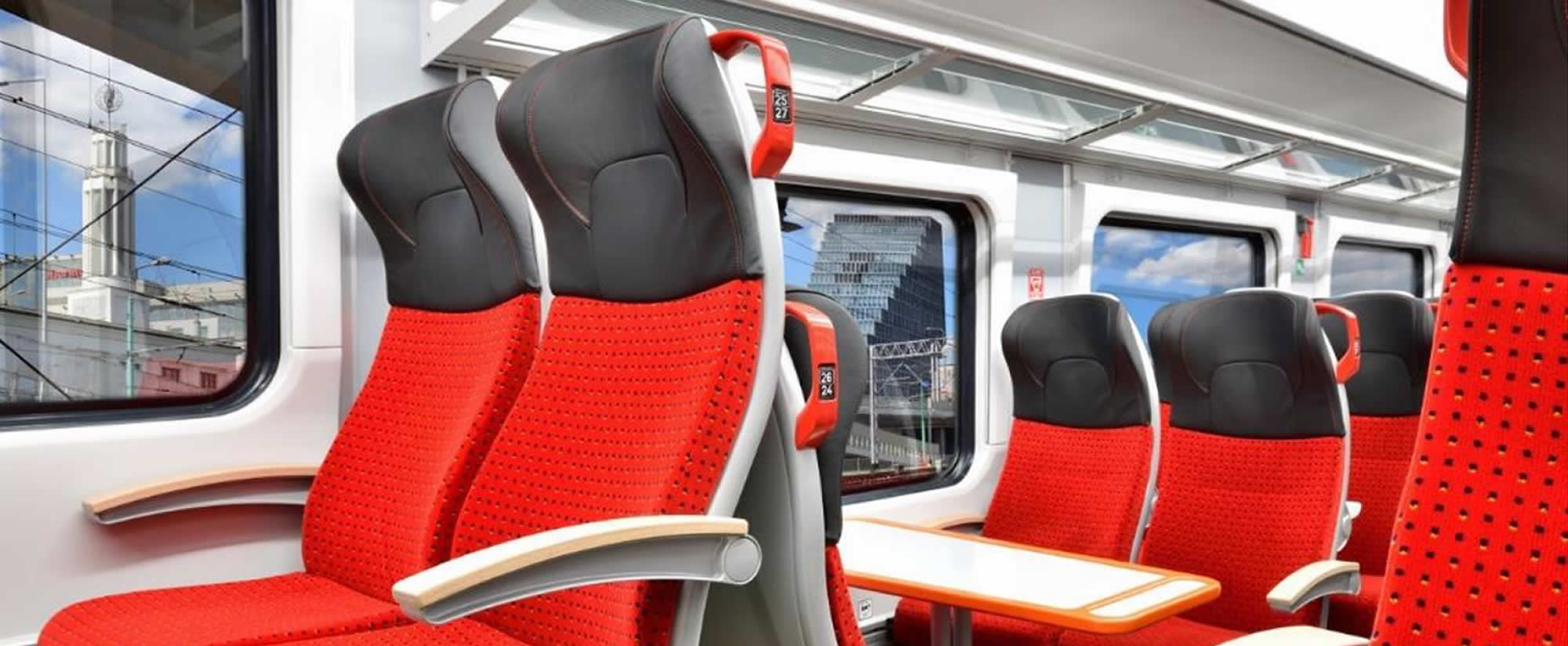 Rail passenger seating with red upholstery and grab handles